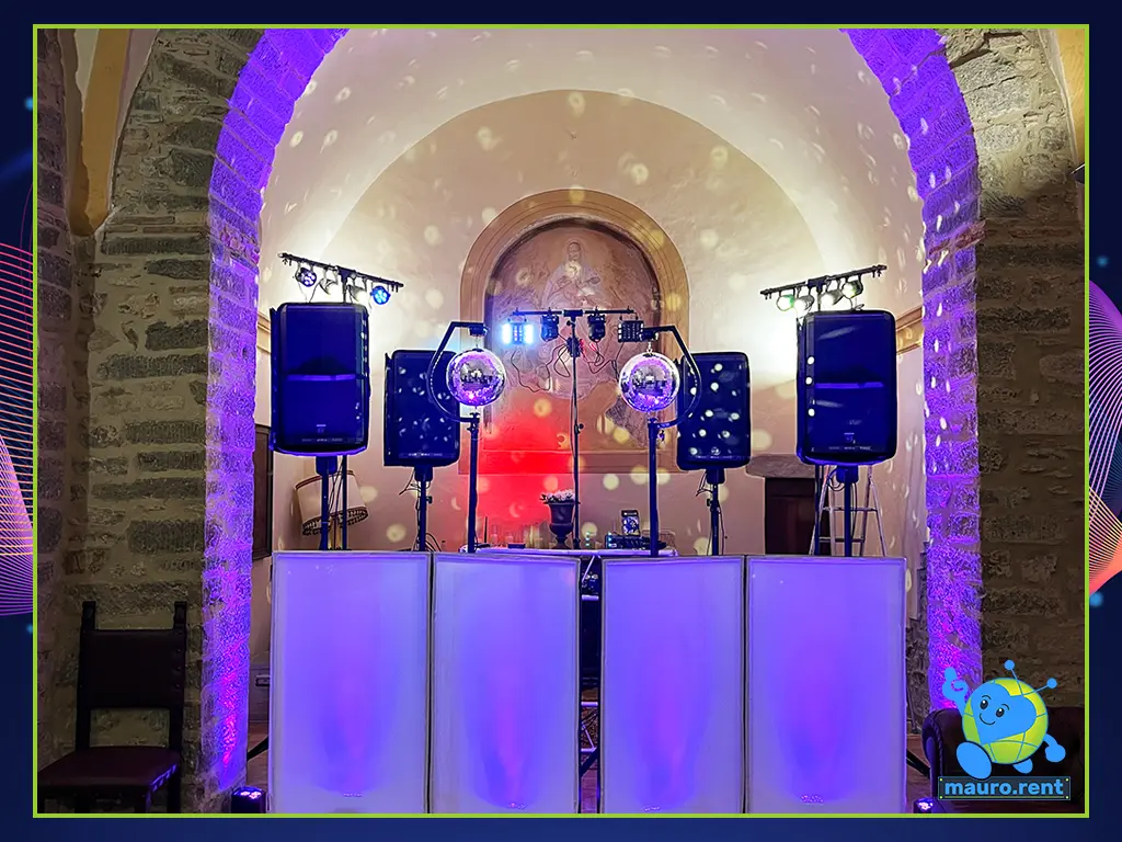 Comprehensive wide shot of the high-energy wedding dance floor setup at Abbazia San Faustino, featuring a sleek facade, RCF Art sound infrastructure, lighting towers, and mirror disco balls.