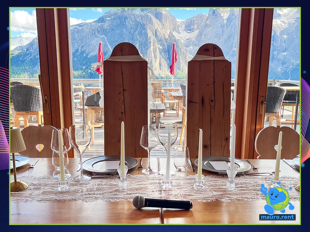 Shure PG58 wireless microphone positioned on the newlyweds' dinner table inside Col Pradat lodge, overlooking the Sella Group Dolomites through a panoramic glass window.