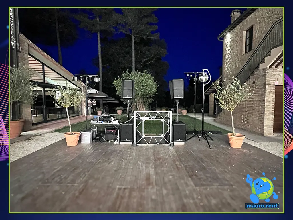 Symmetrical wide shot of the complete wedding DJ booth, audio towers, and lighting matrix fully assembled at Agriturismo Terre di San Galgano.